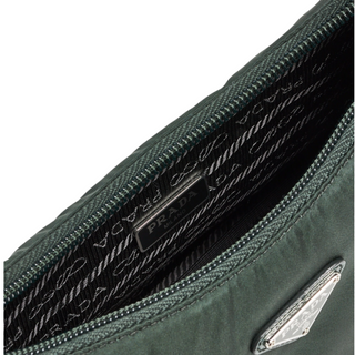 Planet Luxury Brands yeşil Re-Nylon kumaşlı, metal logolu ve Prada iç astarlı Re-Edition 2000 mini çanta detayı