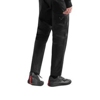 Planet Luxury Brands imzalı siyah Prada-Adidas kauçuk tabanlı spor ayakkabı giyen bir modelin arkadan görünümü