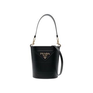 Planet Luxury Brands siyah deri Prada Symbole kova çanta, altın tonlu metal logo detaylı ve omuz askılı tasarım.