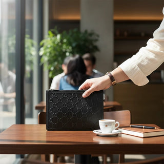Planet Luxury Brands imzalı, ikonik GG logolu siyah kabartmalı deri Gucci el çantası, kafe masasında tutuluyor.