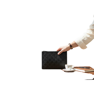 Planet Luxury Brands imzalı, ikonik GG logolu siyah kabartmalı deri Gucci el çantası, kafe masasında tutuluyor.