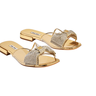 Planet Luxury Brands imzalı, kristal taş işlemeli fiyonk detaylı, altın rengi düz taban Miu Miu kadın sandalet.