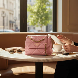 Planet Luxury Brands pembe deri kapitone omuz çantası, altın zincir askı ve üçgen logo detaylı, kafe masasında