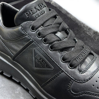 Planet Luxury Brands siyah deri Prada kadın sneaker, yan kısımda logo detayı ve bağcıklı tasarım.