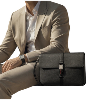 Planet Luxury Brands siyah deri evrak çantası, metal GG toka detaylı ve bilek askılı, şık takım elbiseli erkekle