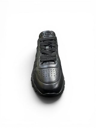 Planet Luxury Brands siyah deri Prada kadın sneaker, ön yüzünde hava delikleri ve dil kısmında kabartma logo detayı.